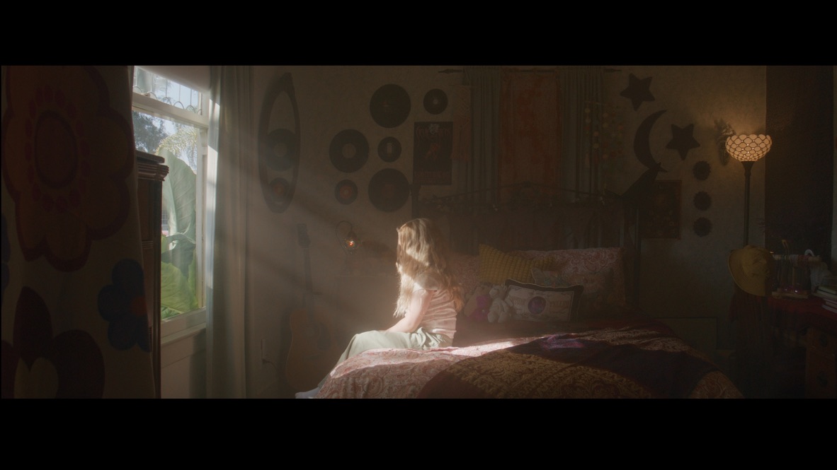 A girl sitting on a bed in a sunlit room