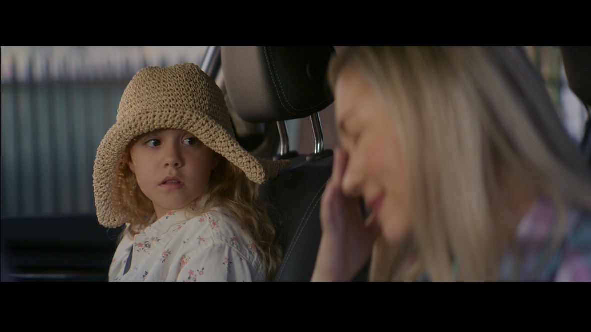 A girl wearing a woven hat beside a woman in a car
